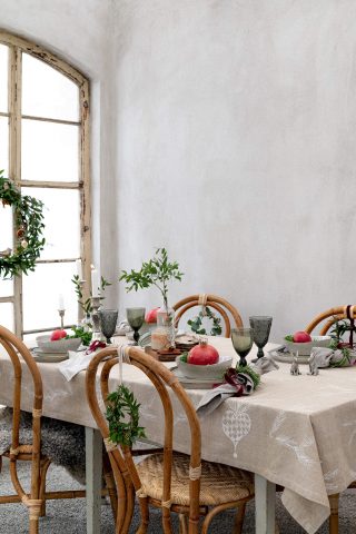 Christmas table by a window, candelabra, plates, glasses och flowers.