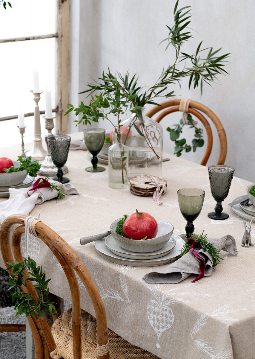 Christmas table by a window, candelabra, plates, glasses och flowers.