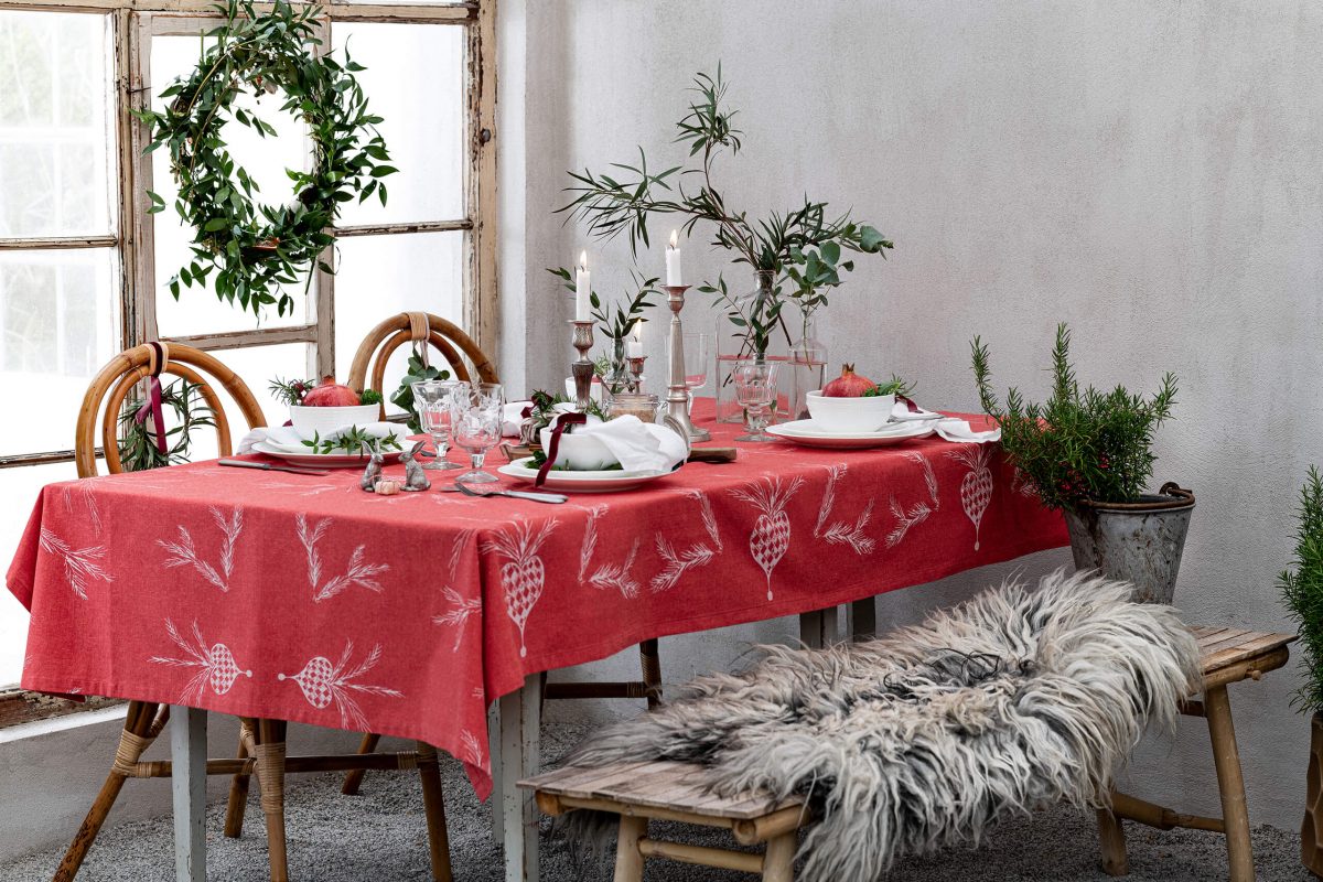 Christmas table by a window, candelabra, plates, glasses och flowers.