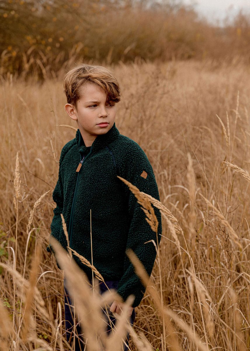 Kid posing in a field, autumn light, wearing soft green fleece