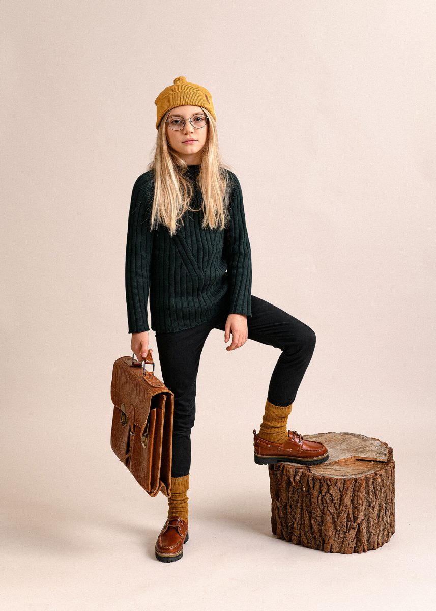 KId portrait in studio, Wearing beanie, posing, holding a bag.