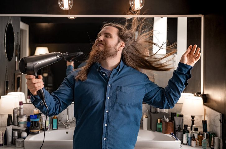 Happy bloke in bathroom. Drying his hair with a great hairdryer.