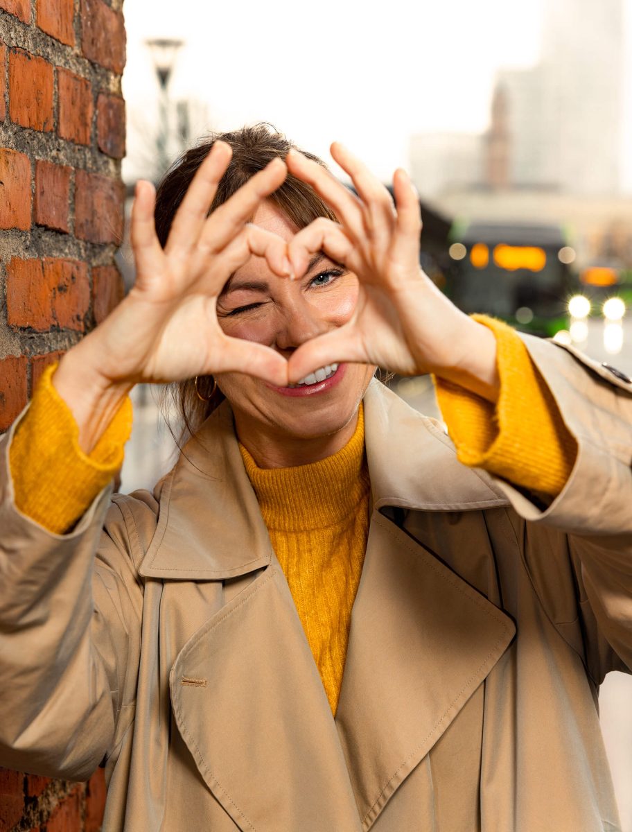 Lady making a heart with her fingers, sunlight, summer, evening, city.